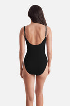 Woman wearing a black one-piece swimsuit with a scoop back