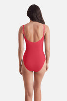Woman turned away wearing a coral-colored one-piece swimsuit