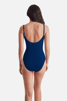Woman turned away wearing a dark blue one-piece swimsuit 