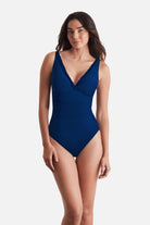 Woman wearing a dark blue one-piece swimsuit with ruffles on the edges