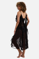 Woman turned left wearing a black sheer ruffled swim dress cover up