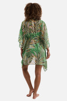 Woman turned away wearing a multicolored leaf print sheer swim cover up