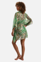 Woman turned left wearing a multicolored leaf print sheer swim cover up