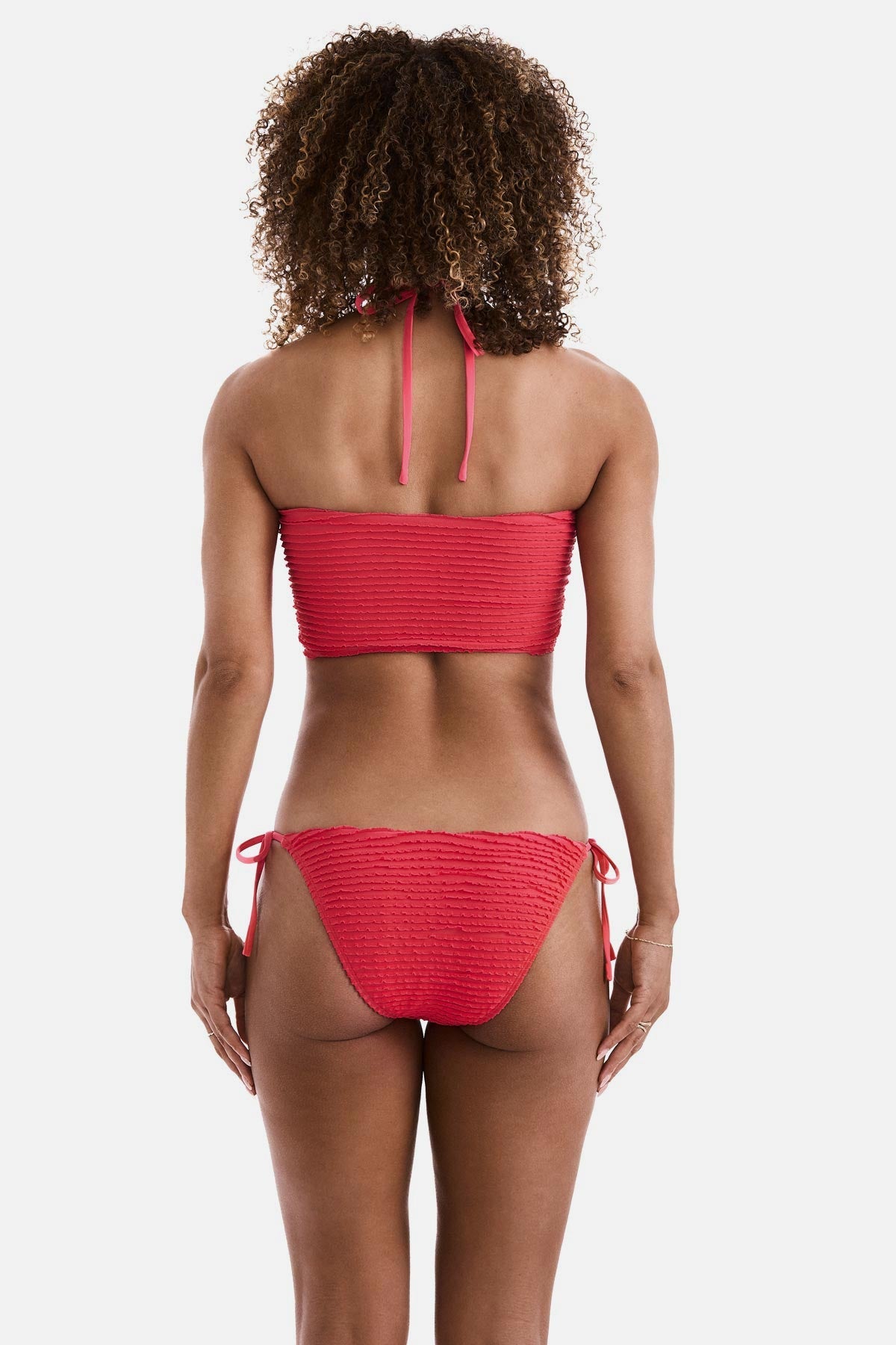 Woman turned away wearing a coral colored midkini swim top with matching swim bottoms