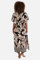 Woman turned away wearing a black and tan palm leaf printed swim dress cover up