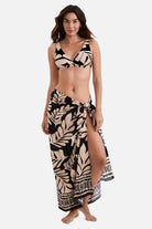 Woman wearing a black and tan palm leaf printed swim cover up with matching bikini top