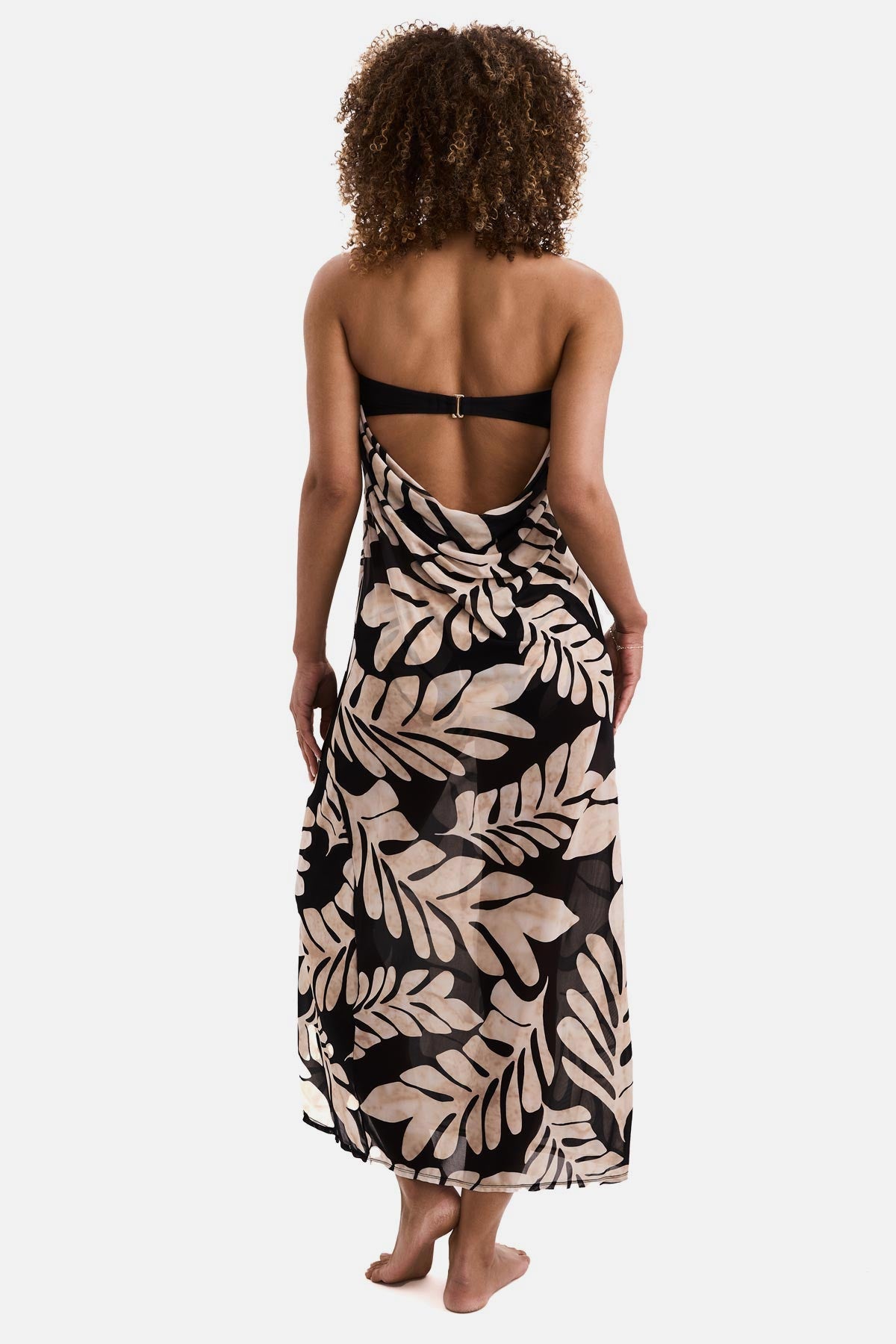 Woman turned away wearing a black and tan palm leaf printed sleeveless swim dress cover up
