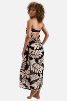 Woman turned left wearing a black and tan palm leaf printed sleeveless swim dress cover up