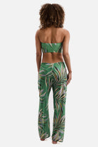 Woman turned away wearing a multicolored leaf printed swim cover up pants with a matching midkini top