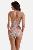 Woman turned away wearing a tie dye one-piece swimsuit with a halter tie