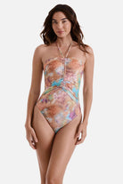Woman wearing a tie dye one-piece swimsuit with a halter tie