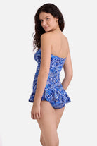 Woman turned left wearing a blue and white floral printed skirted one-piece swimsuit